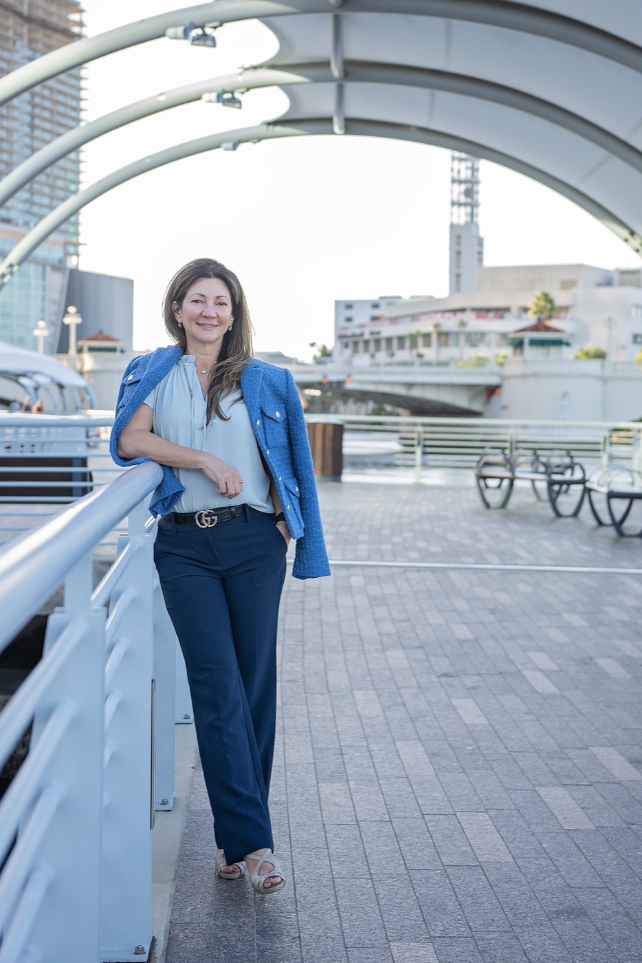 Carrie standing on the Tampa riverwalk in a blue jacket, smiling