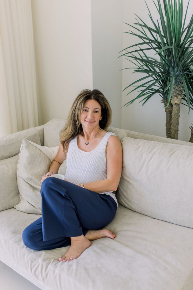 Carrie sitting on a white sofa by the window