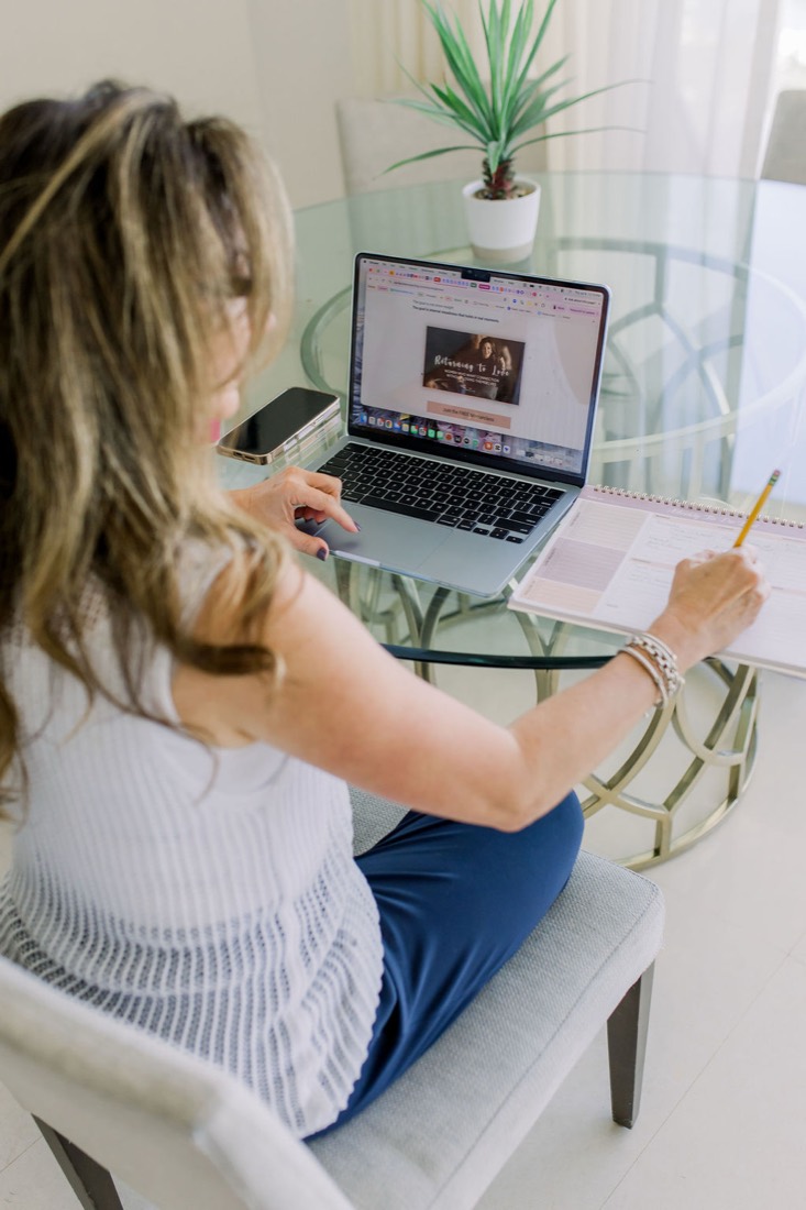 Carrie writing at her laptop by the window