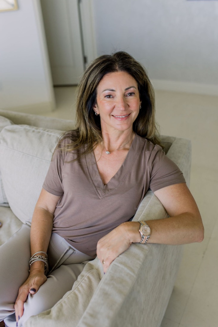 Carrie leaning on the arm of a sofa, smiling