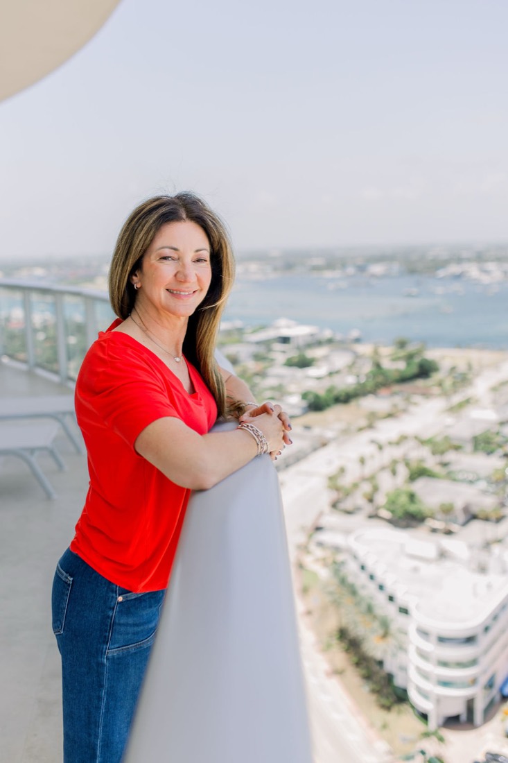 Carrie in a red top on a balcony high above the water
